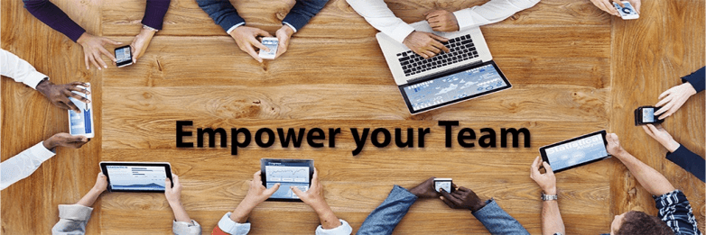 Decorative image of a top-down wooden conference table with 8 people's hands handling mobile devices with the text Empower Your Team.
